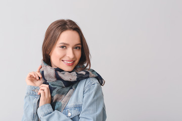 Beautiful young woman with stylish scarf on grey background