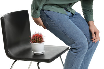 Young man and chair with cactus on white background. Hemorrhoids concept