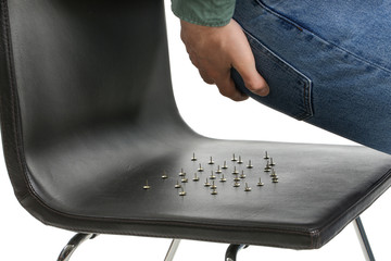Young man and chair with drawing-pins on white background, closeup. Hemorrhoids problem