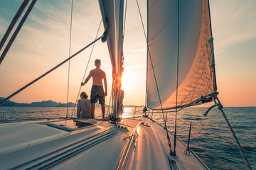 Young couple sailing on the boat at sunset