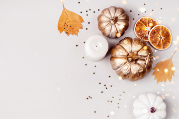 Festive Autumn concept. Decorative pumpkins, golden confetti and dry leaves on gray background. Zero waste decor