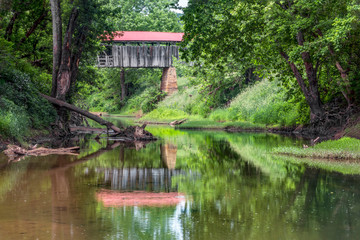 Fototapeta na wymiar Historic Knowlton Covered Bridge is seen reflected in the waters of the Little Muskingom River in rural Monroe County, Ohio. This old bridge collapsed in the summer of 2019.