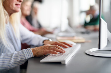 Group of unrecognizable senior people attending computer and technology education class.