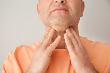 Obraz premium Mature man checking thyroid gland on grey background, closeup