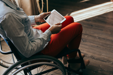 unrecognizable young disabled woman in a wheelchair with a modern tablet.
