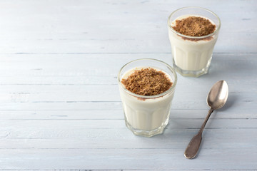 Simple healthy breakfast or snack. Natural yogurt with ground flax seeds in glasses on a light blue background