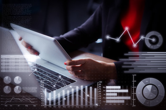 Businesswoman working with laptop and virtual statistic graphics. Close-up of hands of woman sitting at table and working with touchpad in office