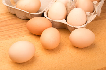 brown chicken eggs in an open cardboard box with eggs on a wooden table. Natural healthy food.