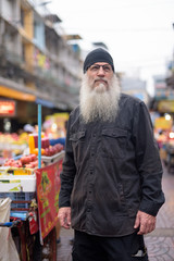 Fototapeta na wymiar Mature bearded tourist man with eyeglasses thinking in Chinatown
