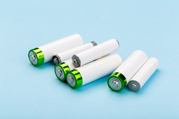 many new and used batteries of different shapes, AA, round batteries on a blue background.