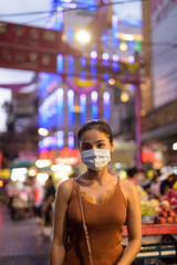 Young Asian tourist woman wearing mask for protection from corona virus outbreak in Chinatown at night