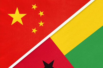 China or PRC vs Guinea-Bissau national flag from textile. Relationship between Asian and African countries.