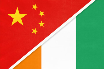 China or PRC vs Ivory Coast national flag from textile. Relationship between Asian and African countries.