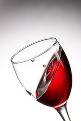 drop falling into a glass with red wine and a splash at an amazing angle
