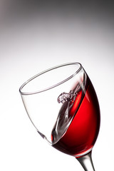 drop falling into a glass with red wine and a splash at an amazing angle