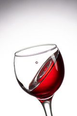 drop falling into a glass with red wine and a splash at an amazing angle