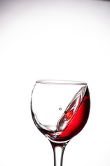drop falling into a glass with red wine and a splash at an amazing angle
