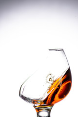 a drop falling into a glass with a broken wall with cognac or whiskey, a splash at an amazing angle