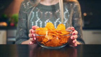 Young lady preferring crisp. Attractive young woman choosing to eat healthy crisp for lunch while sitting at table in stylish kitchen.