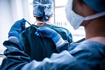 医療用ガウンを着せる医療従事者