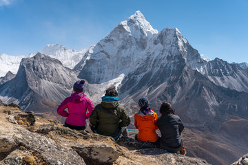 Trekkers sitting on rock and looking to Ama Dablam mountain peak at Nangkart Shank view point, Dingboche village, Nepal