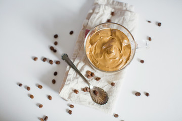 Iced Dalgona Coffee in a glass cup. Trendy fluffy creamy whipped coffee.