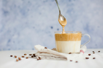Iced Dalgona Coffee in a glass cup. Trendy fluffy creamy whipped coffee.