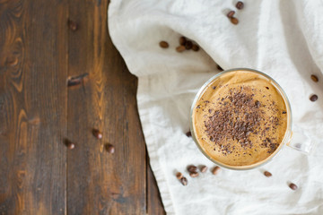 Iced Dalgona Coffee with chocolate powder in a glass cup. Trendy fluffy creamy whipped coffee.