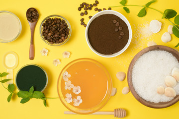 natural organic ingredients-sea salt, coffee scrub, honey and a hard body brush on a yellow background. home skin care for cellulite. concept of skin care, home Spa. the view from the top.