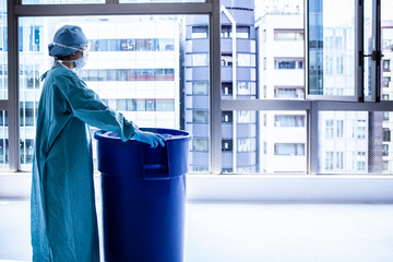 ウイルス感染防護服を着た女性がゴミの回収をしている