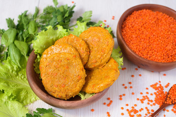 vegan lentil burgers in a wooden plate with green salad on a light background. vegetarian healthy food. lentils in a wooden plate. the view from the top.