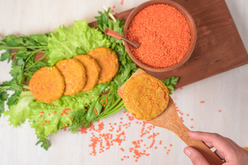 vegan lentil burgers in a wooden plate with green salad on a light background. vegetarian healthy food. lentils in a wooden plate. the view from the top.