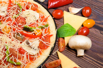 vegan pizza with vegetables, tomatoes, mushrooms, pepper. top view large view . ingredients for vegetarian pizza on a dark background.