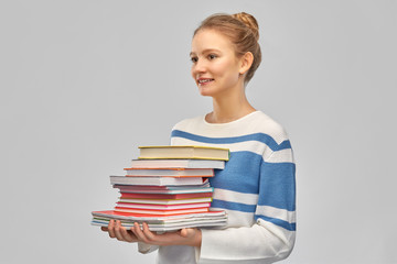 education, travel and tourism concept - happy smiling teenage student girl with books over grey background