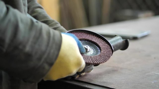In the workshop. Close-up. The man changes the disk on the Angle grinder