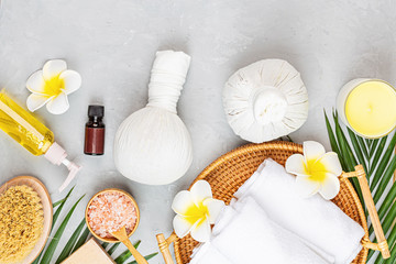 Spa massage Aromatherapy body care background. Spa herbal balls, cosmetics, towel and tropical leaves on gray concrete table. Top view, flat lay, overhead, copy space. Beauty and health care concept