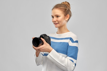 photography and people concept - smiling teenage girl in pullover with digital camera over grey background