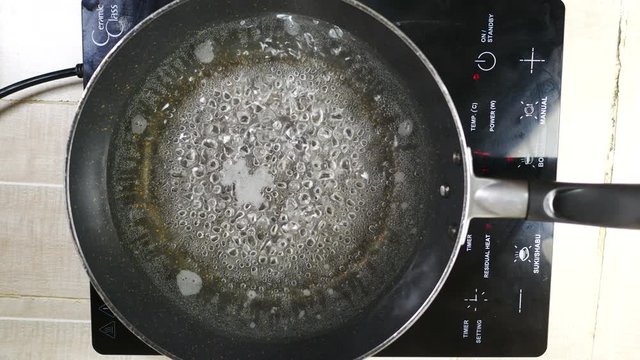 boiled water with bubble in teflon pan with smoke,red light indicator power on and boil menu button,high temperature