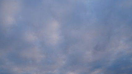 A beautiful evening blue sky at sunset with flaming bright light clouds. Warm evening.