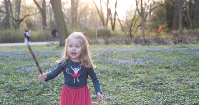 Blonde girl happily whirls in a beautiful dress in the spring park