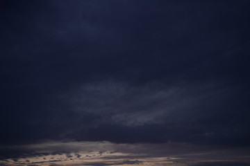 Obraz premium A beautiful evening blue sky at sunset with flaming bright light clouds. Warm evening.