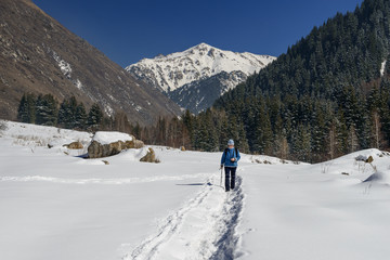 Fototapeta na wymiar A woman walks along a mountain trail at winter.