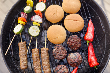 cooking, barbecue and food concept - close up of shish kebab meat, vegetables on bamboo skewers,...