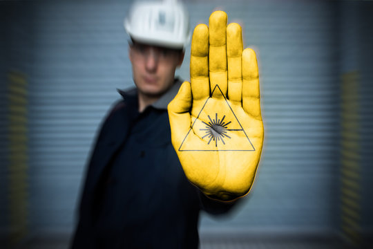 warning sign pictogram Warning of laser beam (in german Warnzeichen, Warnung vor Laserstrahl) Painting on workers hand