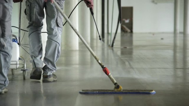 Workers coat the floor of an industrial building.