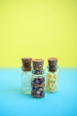 Vertical picture with soft focus of three tiny glass jar with buckwheat, millet, sugar on blue and yellow background, top view. Concept of nutrition, vegetarian products. Empty space for text, design