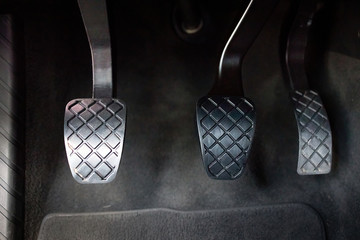 Modern luxury car interior element metal gas clutch and brake pedal. Sport car with manual gearbox controls.