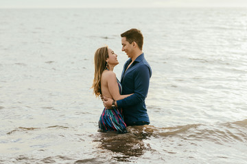 happy couple with half body in the water hugging, looking each other straight in the eye