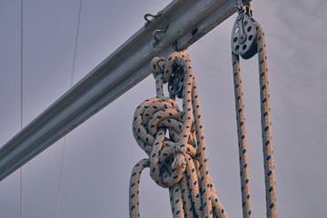 closeup yacht equipment. Lines in snatch block at sunset. Yachting concept and sea background.