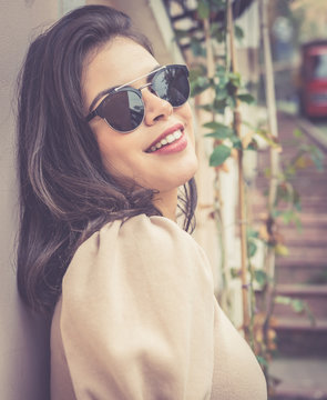 Attractive female person with red lips and brown hair is looking down to camera with colorful  wall in the background.retro style background image.